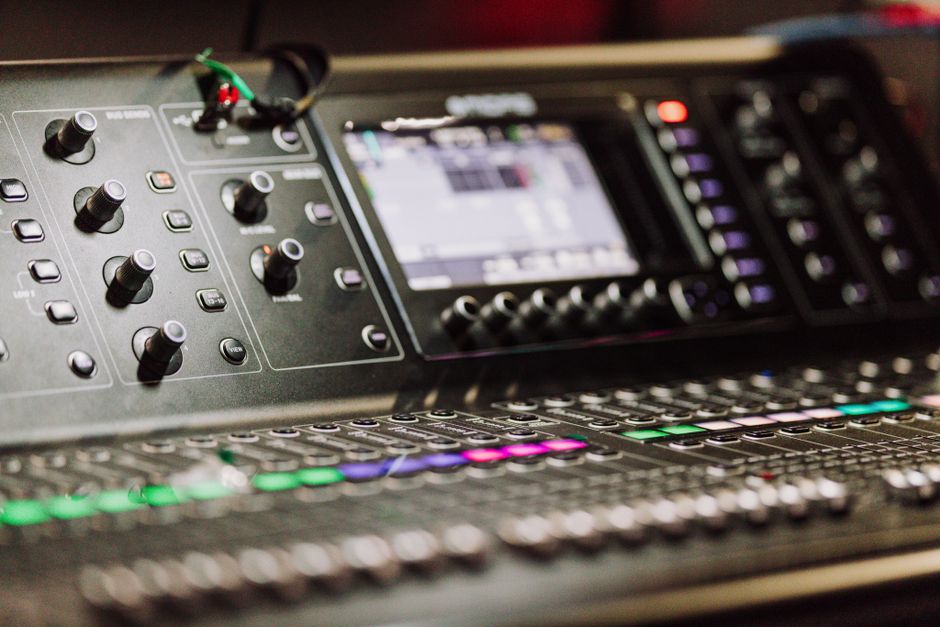 Close-up of a professional audio mixer console with digital screen for music production.