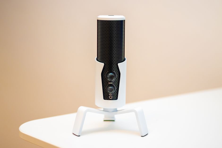 Minimalist close-up of a sleek black microphone on a modern white table, ideal for podcasts and broadcasting.